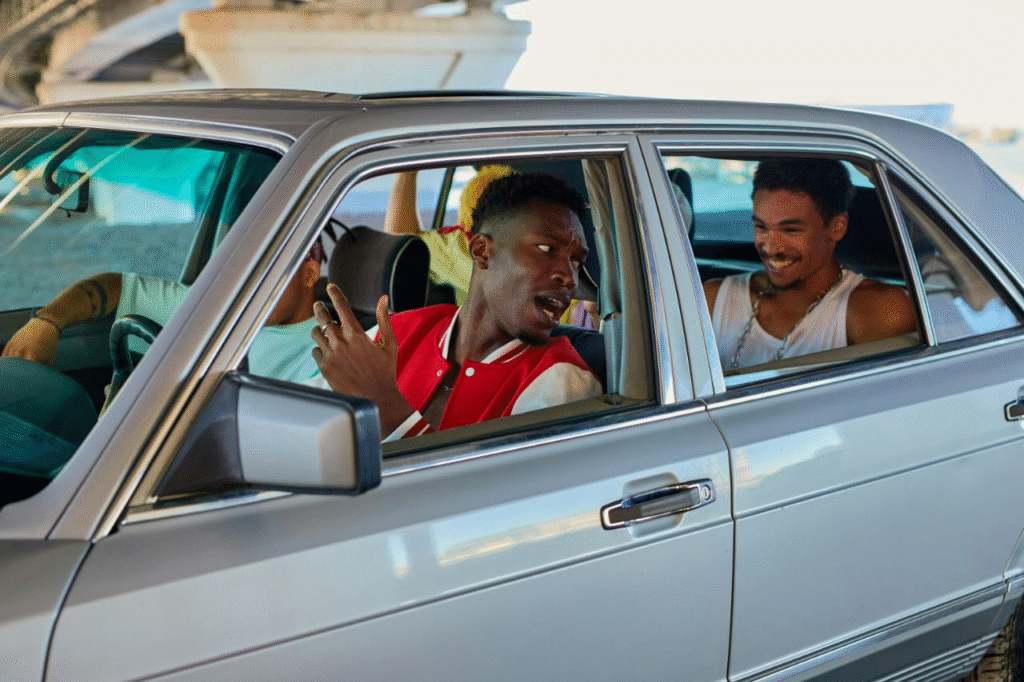 Young man holding car keys and smiling near his car after buying insurance